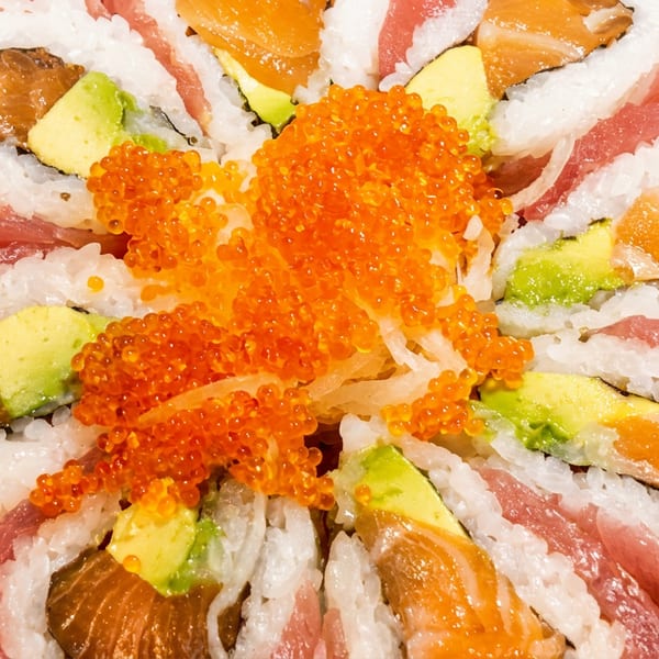 Flower-shaped sushi rolls with salmon, avocado, and tuna, topped with bright orange roe.